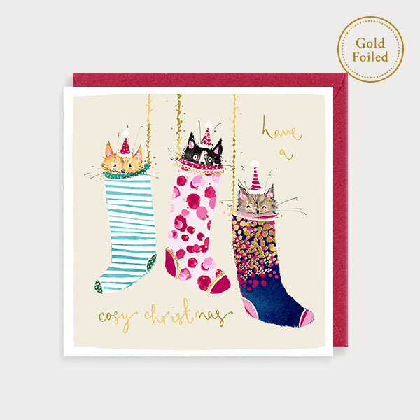 Image of illustrated foiled christmas card with three cats in stockings and the caption have a cosy christmas